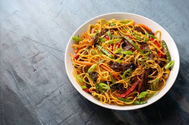 Kızarmış erişteyi sığır eti ve sebzeyle karıştırın. Asya usulü yemek.