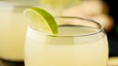 Zencefilli ve limonlu gazoz, yanında limon dilimleri olan bardaklarda köpüklü içecek.