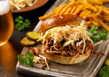 Ev yapımı mangal soslu domuz burger lahana salatası, patates kızartması ve bira.