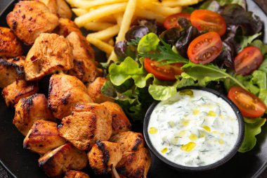 Tavuk fileto, kebap, patates cipsi, salata ve taze ev yapımı tzatziki.