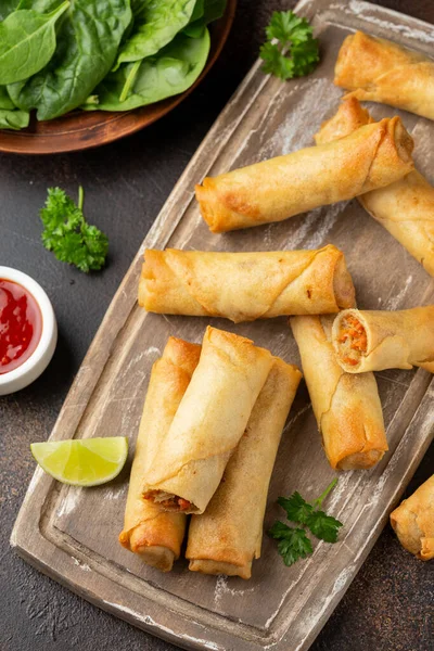 Fried vegetable spring rolls with sweet chili and soya sauce on wooden board