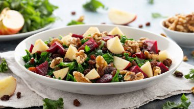 Elmalı lahana salatası, pancar, ceviz ve beyaz tabakta kuru üzüm. Sağlıklı yemek.