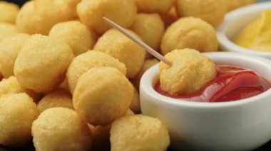 Ketçaplı çıtır patates topları ve siyah tabakta hardal.