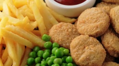 Ketçaplı kızarmış tavuk nugget, patates kızartması ve bezelye. dönen video.