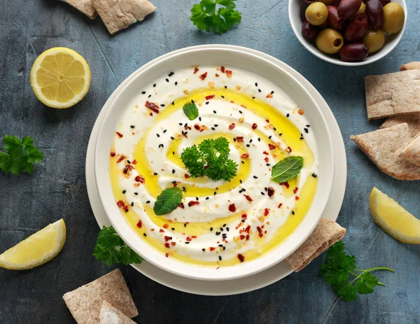 Labneh roomkaas dip met olijfolie, zout, kruiden geserveerd met olijven, pitabrood in witte kom — Stockfoto