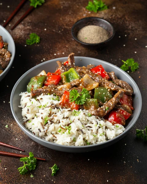 Chinesisches Rindersteak mit Zwiebeln, roter und grüner Paprika, Reis in Schüssel anbraten — Stockfoto