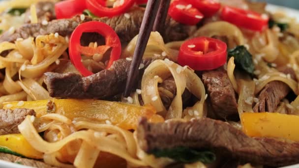 Picking Stir fry Beef Chow Fun with rice noodles, bean sprouts, spring onions and chili from a bowl using a chopstick — Stock Video