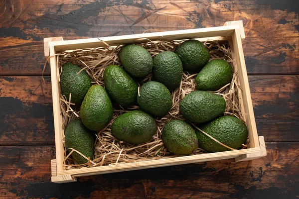 Свежий авокадо в деревянной коробке на деревенском столе — стоковое фото
