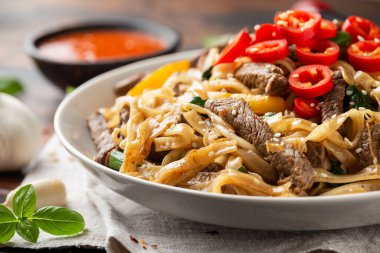 Kızarmış sığır eti, erişte, fasulye filizi, taze soğan ve biber ile karıştırın..