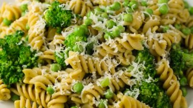 Yeşil bezelye, pesto soslu brokoli makarna ve parmesan peyniri. Sağlıklı yemek. dönen video.
