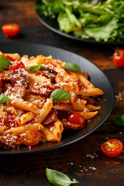 Worst penne Pasta met tomatensaus, parmezaanse kaas en basilicum op zwarte plaat — Stockfoto