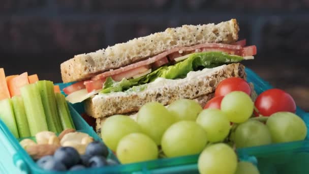 Zdrowa szkoła lub praca lunch box z kanapką, świeże warzywa, owoce i orzechy. Obracające się wideo — Wideo stockowe