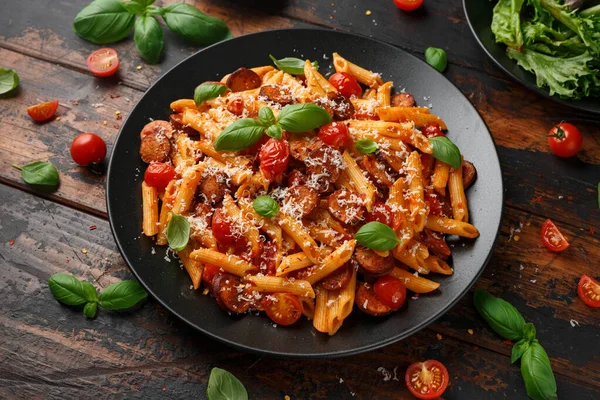 Worst penne Pasta met tomatensaus, parmezaanse kaas en basilicum op zwarte plaat — Stockfoto