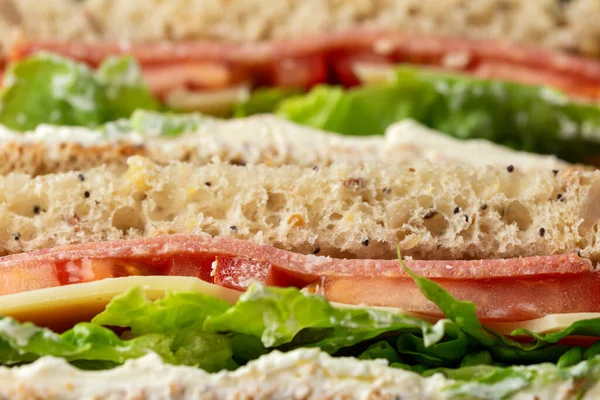 Sandwiches with lettuce, slices of fresh tomatoes, salami and cheese. — Stock Photo, Image