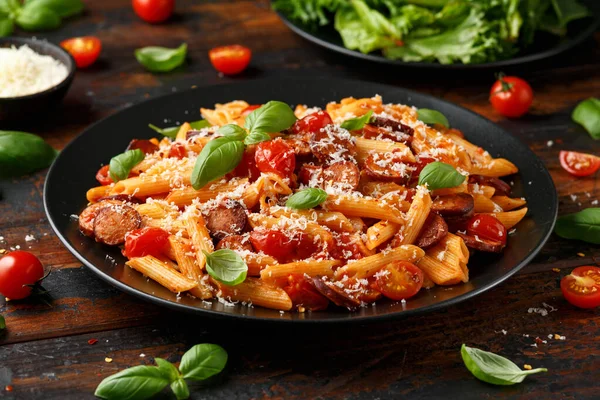 Worst penne Pasta met tomatensaus, parmezaanse kaas en basilicum op zwarte plaat — Stockfoto