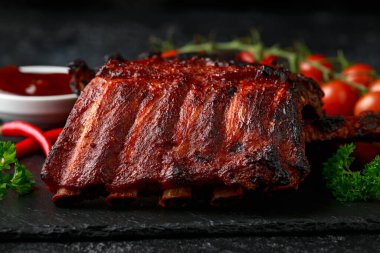 Izgara domuz pirzolası, bol soslu ve taş tahtada otlar.