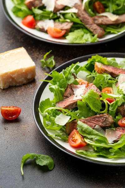 Итальянский салат из говядины Tagliata с дикой ракетой, помидорами черри и сыром пармезан — стоковое фото