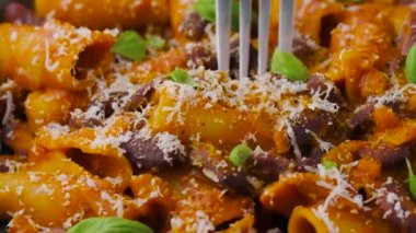 Fasulyeli, domatesli ve parmesanlı peynirli bir çatal kullanarak makarna yemek..
