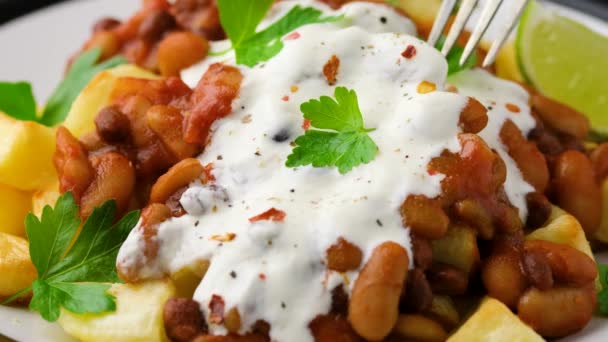 Eating Spicy Bean Chilli with Baked Potato, sour cream and lime — Stock Video