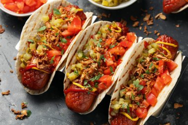 Sosisli, turşulu, domatesli ve kızarmış soğanlı Taco Hot Dog..
