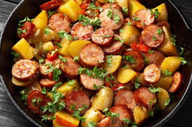 Koyu ahşap masada kızarmış patates ve sosis..