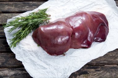 Buruşuk kağıt üzerinde pişmemiş karaciğer Rosemary ile dekore edilmiştir. eski ahşap tablo