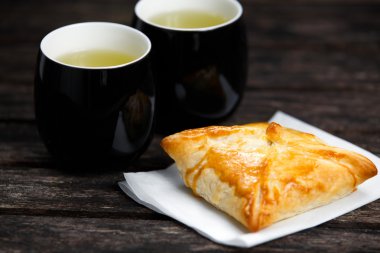 Eski ahşap masa üzerinde sığır eti, patates ve soğan ve yeşil çay bardağı ile ev yapımı pasta.