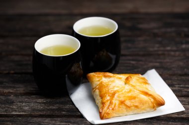 Eski ahşap masa üzerinde sığır eti, patates ve soğan ve yeşil çay bardağı ile ev yapımı pasta