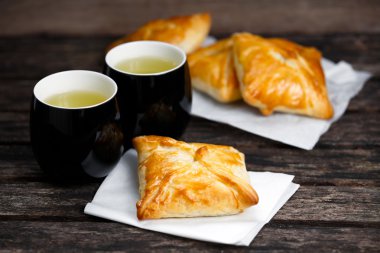 Eski ahşap masa üzerinde sığır eti, patates ve soğan ve yeşil çay bardağı ile ev yapımı pasta