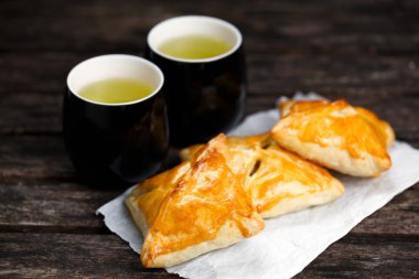 Eski ahşap masa üzerinde sığır eti, patates ve soğan ve yeşil çay bardağı ile ev yapımı pasta.