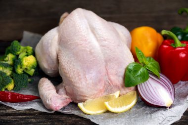 Free Range Farm Whole Chicken decorated with vegetables. on crumpled paper.