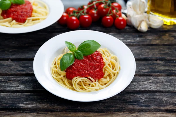 Spaghetti with marinara sauce and basil leaves on top, decorated with vegetables, olive oil. on wooden table. Rechtenvrije Stockfoto's