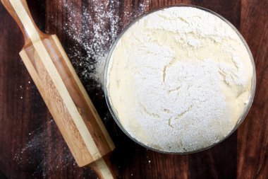 Taze olarak hazırlanan hamur bir ahşap tahta üzerinde. Oklava ve un