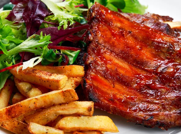 Côtelette de porc rôtie, pommes de terre frites sur assiette blanche avec légumes . — Photo