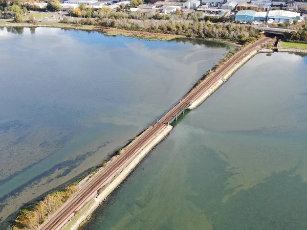 Вид с воздуха на железнодорожную линию, пересекающую мелководье в гавани Пула на дамбе — стоковое фото