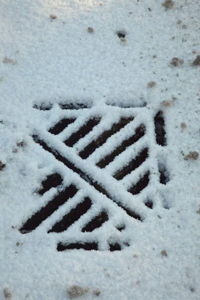 Een gedeeltelijk met sneeuw bedekte roosterafdekking — Stockfoto