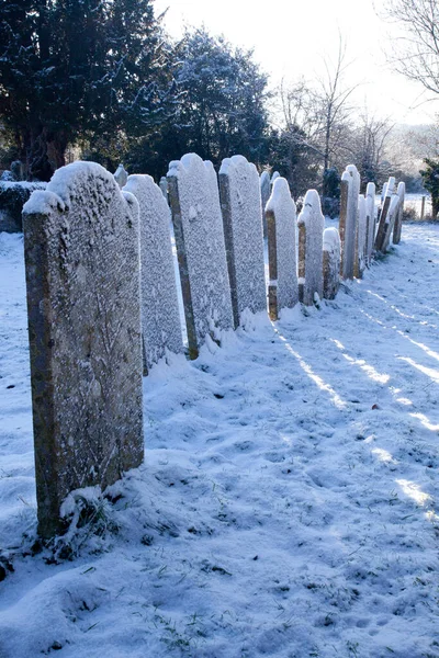 Uma fileira de lápides antigas cobertas de neve em um cemitério — Fotografia de Stock