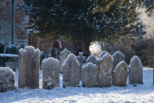 Uma fileira de lápides antigas cobertas de neve em um cemitério — Fotografia de Stock
