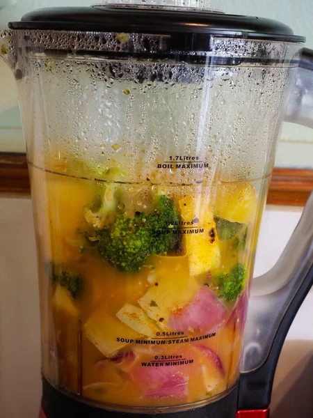 Close-up of a soup making machine with broccoli and butternut squash and onions inside — Stock Photo, Image