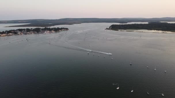 Une courte vidéo aérienne 4k de bateaux à moteur traversant le port de Poole dans la soirée — Video