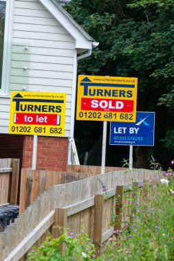 İngiltere 'de satılık bir evin yakınındaki satılık tabelalar için emlakçı