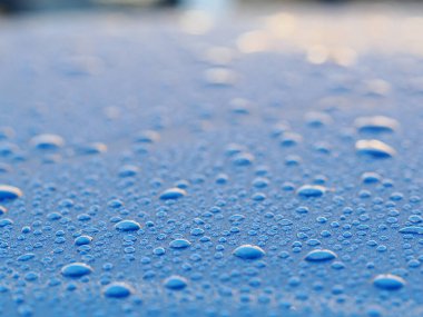 Mavi bir arabanın çatısındaki yağmur damlalarının makro resmi