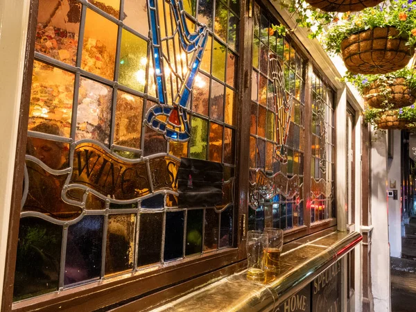 Pencere kenarında kullanılmış bira bardaklarıyla dekoratif bir bar penceresi boyalı cam ve verniklenmiş ahşap.