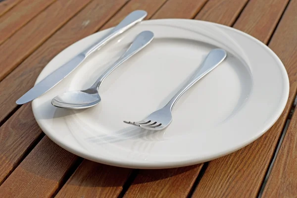 Ложка виделки і ножа на порожній білій тарілці — стокове фото