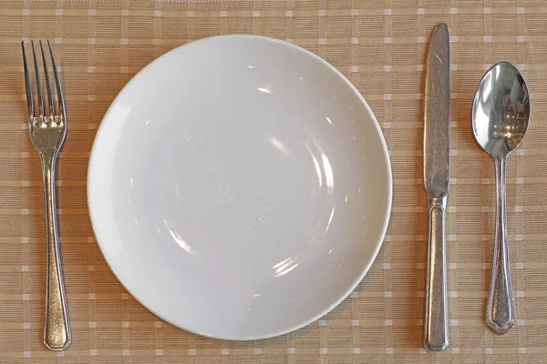 Cuchillo tenedor cuchara y plato blanco vacío — Foto de Stock