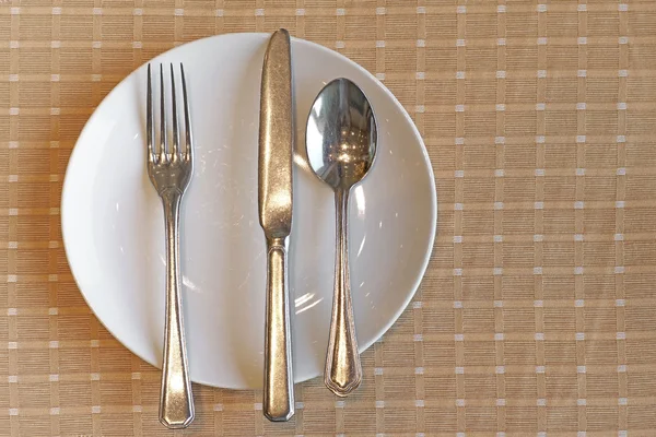 Κουτάλι πηρούνι και μαχαίρι στις άδειο άσπρο πιάτο — Φωτογραφία Αρχείου