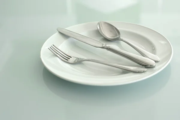 Spoon fork and knife on empty white plate — Stock Photo, Image