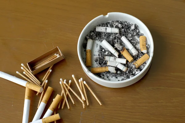 Kouřil cigarety v bílém popelník a zápalka — Stock fotografie