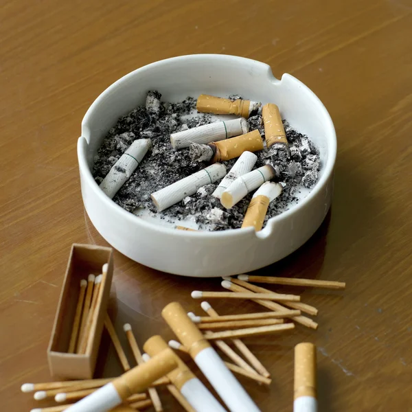 Kouřil cigarety v bílém popelník a zápalka — Stock fotografie