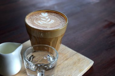 Tahta masada bir fincan sıcak latte sanat kahvesi.